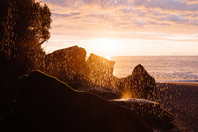 A stunning sunset through a small waterfall near Punakaiki